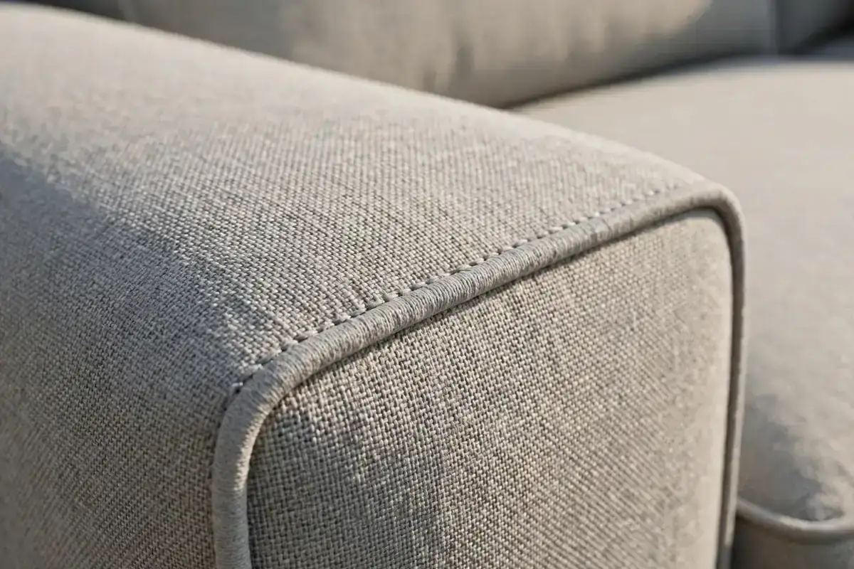 Woven gray sofa fabric with a stitched seam and piping up close